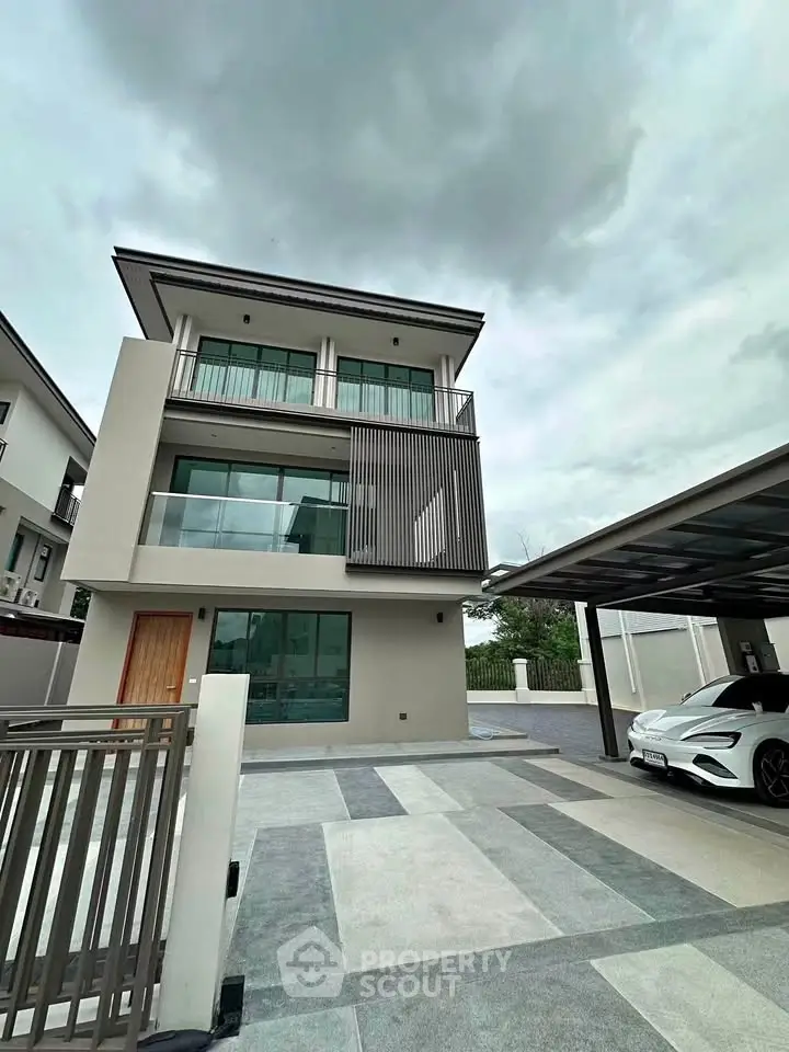 Modern three-story house with sleek design and spacious driveway, featuring a covered carport and contemporary facade.