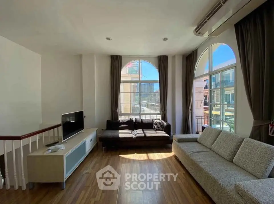 Spacious living room with large windows and modern furniture, perfect for relaxation.