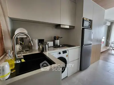 Modern kitchen with sleek appliances and washing machine in compact layout.