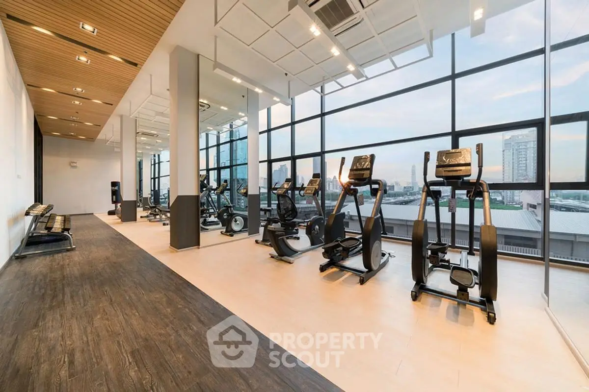 Spacious modern gym with large windows offering stunning city views, equipped with state-of-the-art fitness machines.