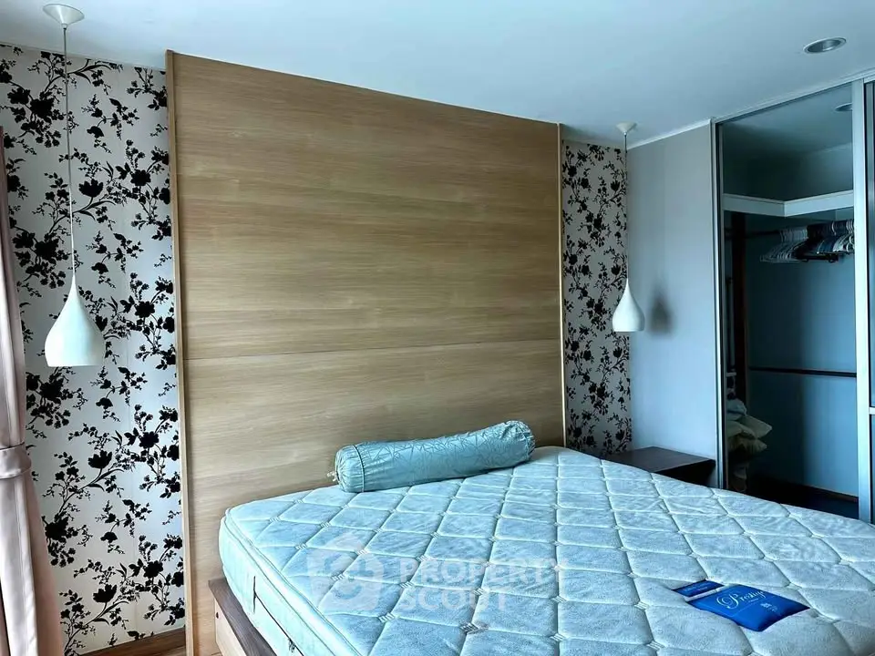 Spacious bedroom with elegant floral wallpaper and modern lighting fixtures.