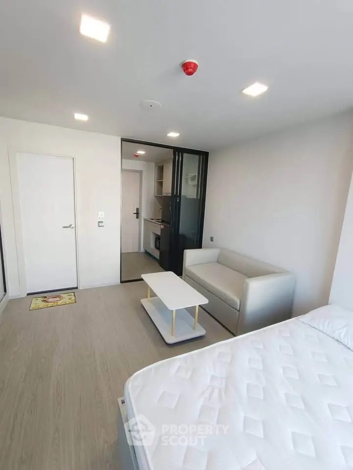 Modern studio apartment with sleek design and open layout, featuring a cozy living area and compact kitchen.