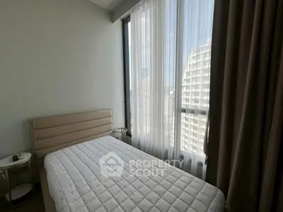 Modern bedroom with large window offering city view, featuring a comfortable bed and elegant decor.