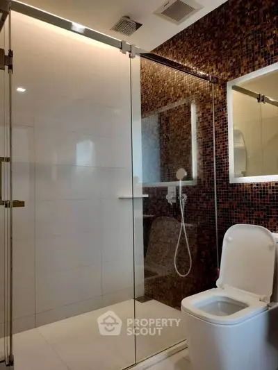 Modern bathroom with glass shower and mosaic tile accent wall