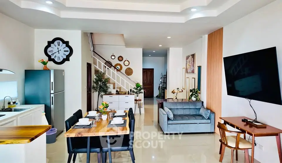 Spacious open-plan living and dining area with modern decor and large wall-mounted TV.