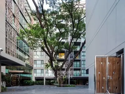 Modern apartment building with lush courtyard and large tree, offering serene urban living.