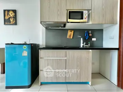 Modern kitchen with sleek cabinetry, compact fridge, and microwave in a stylish apartment.