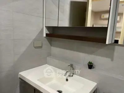 Modern bathroom with sleek sink and mirror, featuring minimalist design and neutral tones.