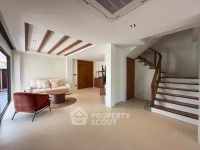 Spacious modern living room with elegant staircase and cozy seating area.