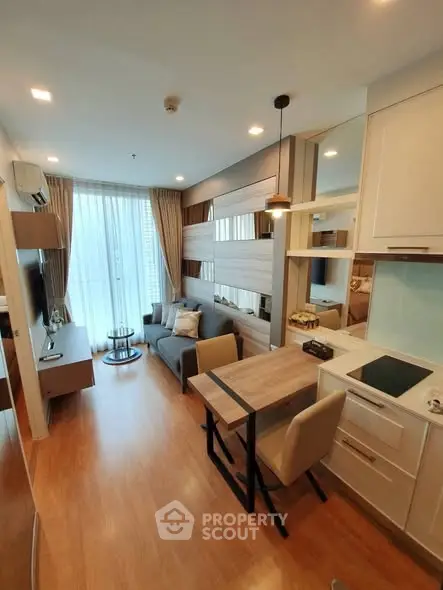 Modern living room with open kitchen in a stylish apartment, featuring sleek furniture and natural light.
