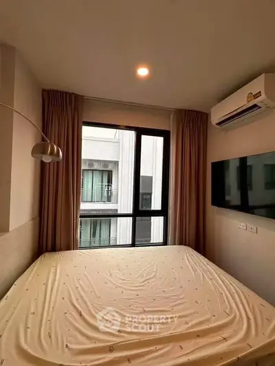 Cozy bedroom with large window and modern amenities in urban apartment