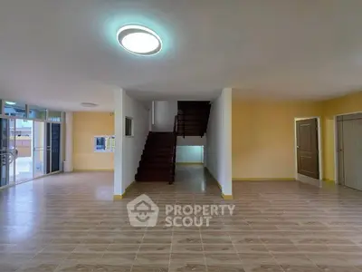 Spacious open-plan living area with modern lighting and staircase, ideal for family gatherings.