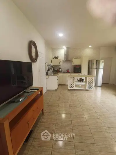 Spacious open-plan living area with tiled flooring, featuring a modern kitchen with stainless steel appliances and ample storage space.