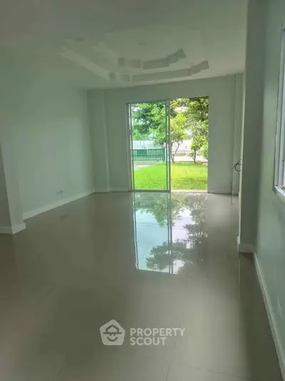 Spacious empty room with large windows overlooking a lush garden, perfect for customization.