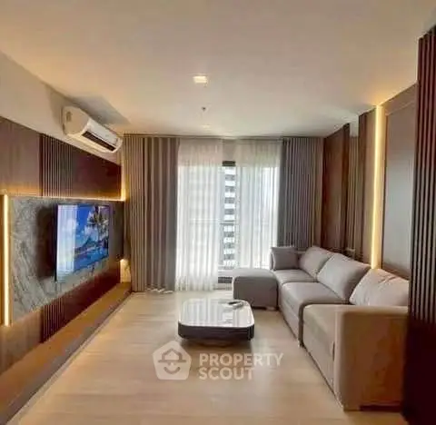 Modern living room with sleek design and large sofa, featuring a wall-mounted TV and elegant lighting.