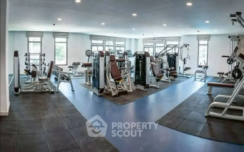 Spacious modern gym with state-of-the-art fitness equipment and large windows for natural light.