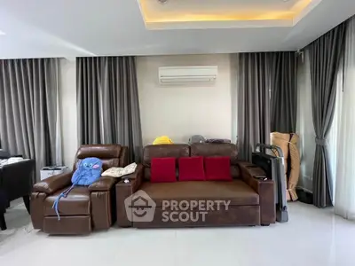 Spacious living room with modern leather seating and elegant curtains