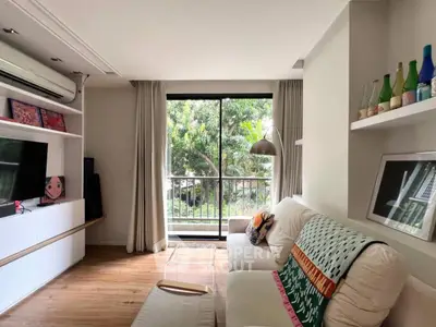 Charming living room with cozy decor and lush garden view from balcony.