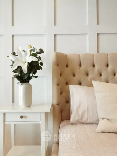 Elegant bedroom with tufted headboard and stylish nightstand featuring a floral arrangement.