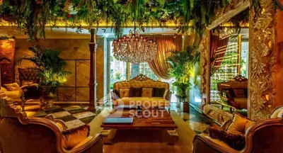 Luxurious living room with opulent decor and lush greenery, featuring elegant furniture and a grand chandelier.