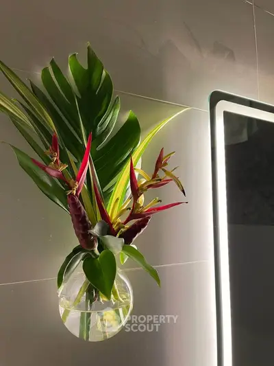 Elegant bathroom decor with modern lighting and tropical plant arrangement.
