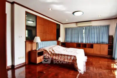 Spacious bedroom with wooden flooring and elegant furnishings in a modern home.