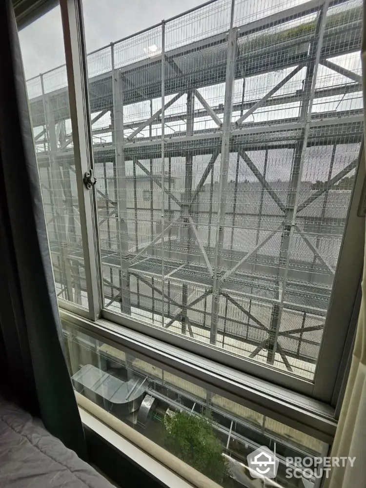 Urban apartment window view with industrial metal structure outside