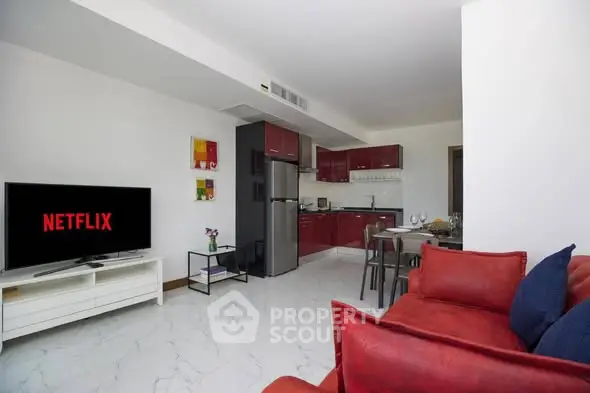 Modern living room with open kitchen, red sofa, and TV displaying Netflix, ideal for cozy entertainment.