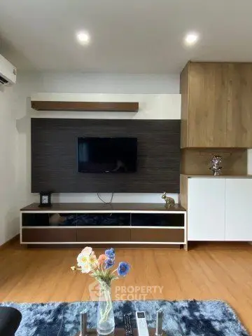 Modern living room with sleek TV unit and wooden flooring, featuring stylish decor and ambient lighting.