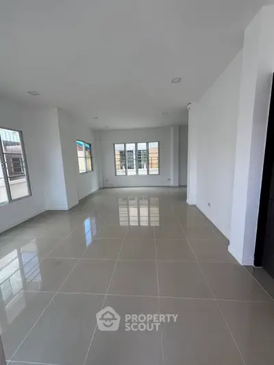 Spacious empty living room with large windows and glossy tiled floor