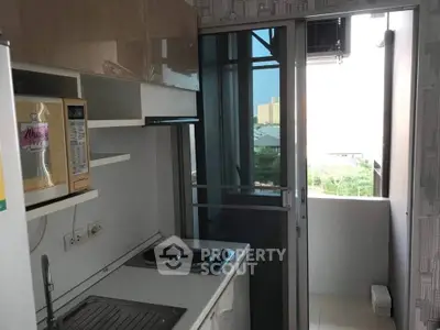 Compact kitchen with modern appliances and balcony view in urban apartment