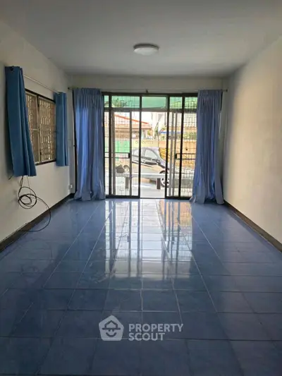 Spacious empty room with blue tiled floor and large windows, perfect for customization.