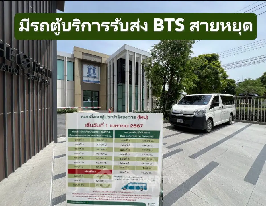 Modern building exterior with van and informational sign in front, showcasing convenient transportation access.