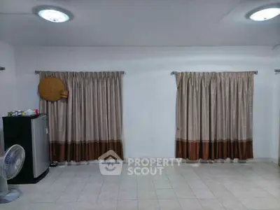 Spacious tiled room with curtains and a mini fridge, ideal for versatile use.