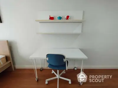 Minimalist study area with a sleek white desk, comfortable blue chair, and charming decorative shelves, perfect for focused work or study sessions.