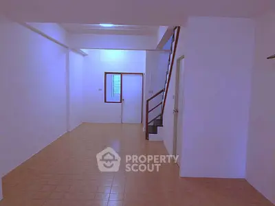Spacious interior with tiled flooring and staircase, ideal for customization.