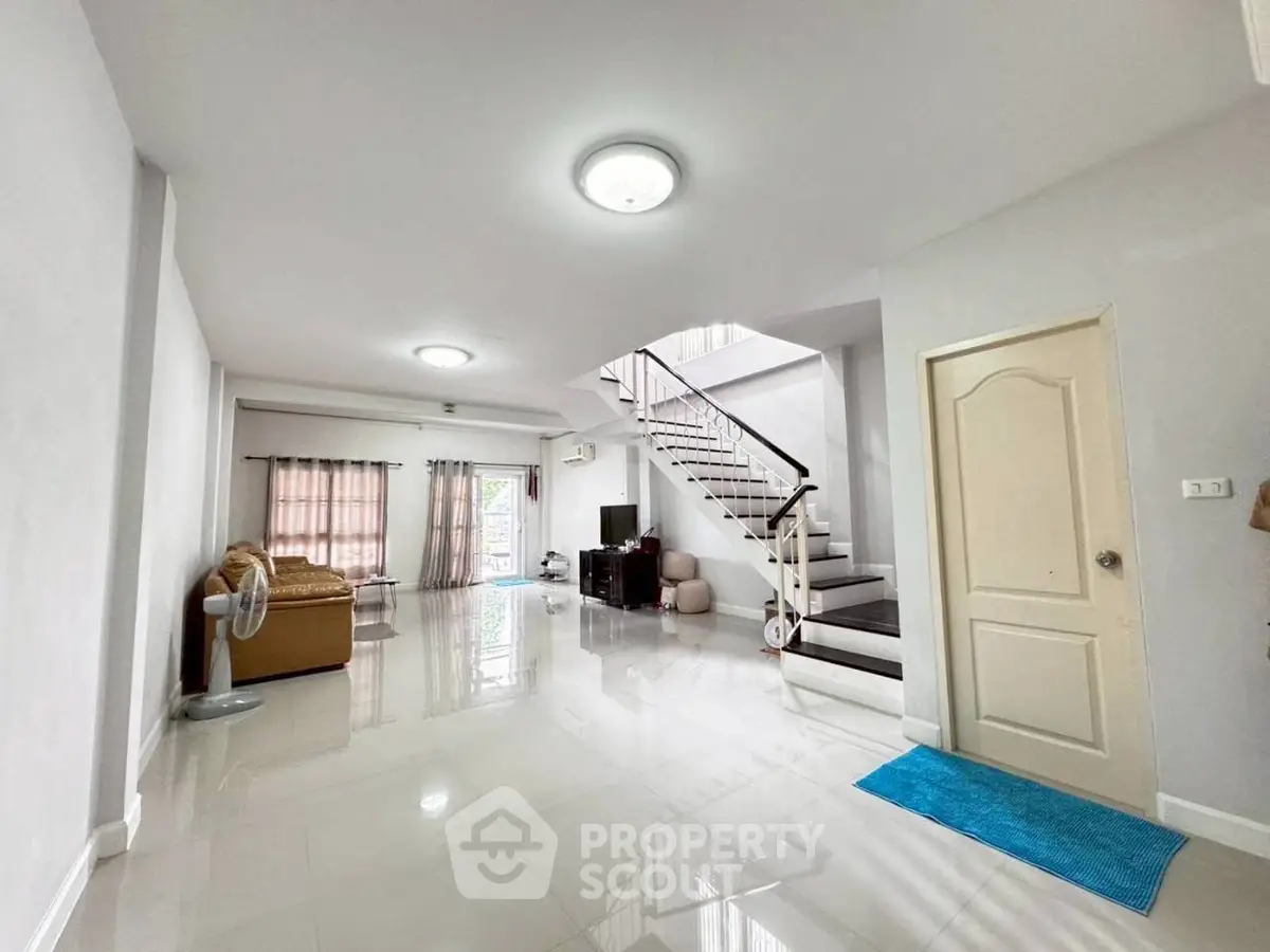 Spacious living room with modern staircase and natural light