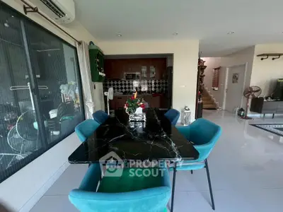 Modern dining area with marble table and teal chairs in open-plan living space