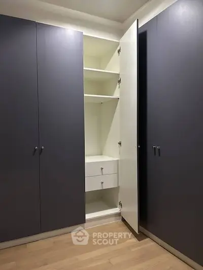 Spacious corner wardrobe with open shelves and drawers in modern bedroom.