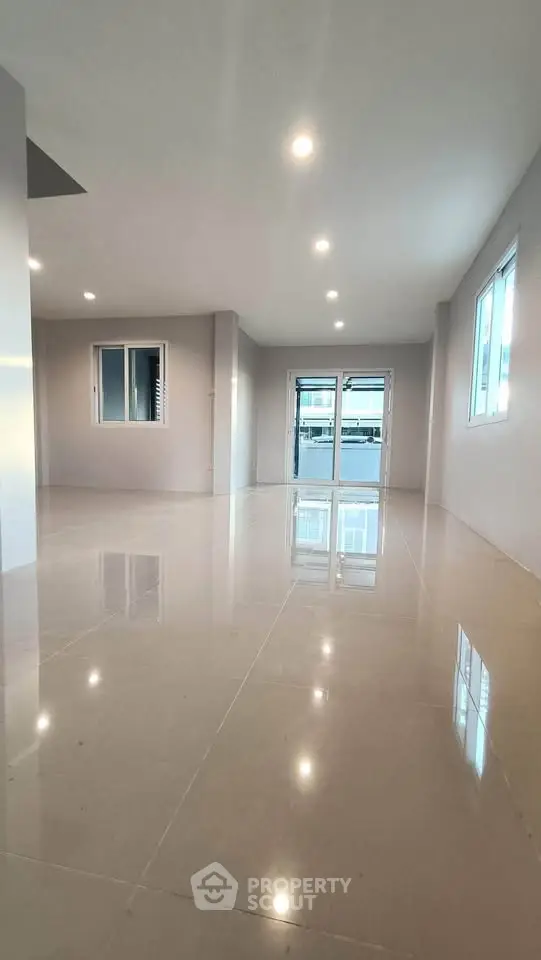 Spacious modern living room with glossy tiled floors and large windows.