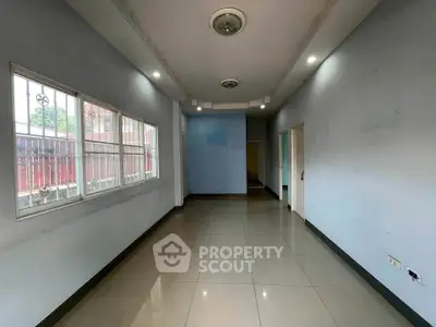 Spacious empty room with tiled flooring and large windows, ideal for customization.