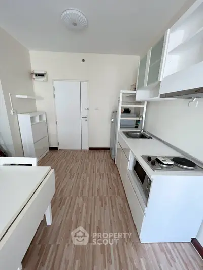 Modern kitchen with sleek white cabinetry and compact appliances in a cozy apartment setting.