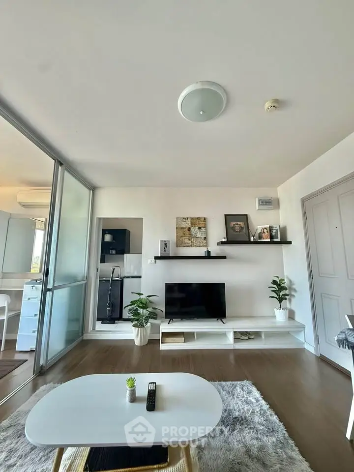 Modern living room with sleek decor and open layout, featuring a TV and stylish shelving.