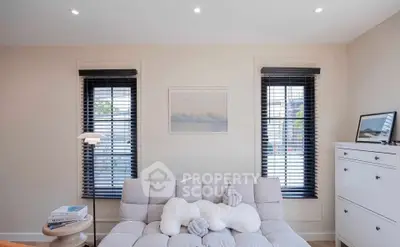 Chic living room with modern decor and ample natural light, featuring a cozy sofa and stylish blinds.