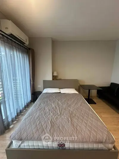 Modern bedroom with large window, air conditioning, and cozy furnishings in a stylish apartment.