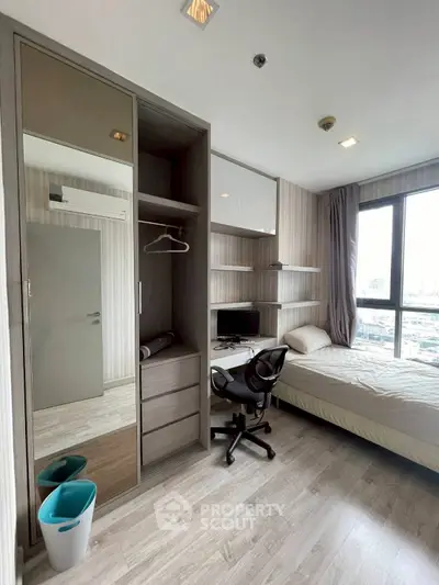 Modern bedroom with study area, featuring large window and sleek furniture design.