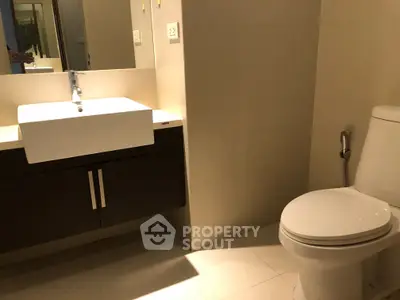 Modern bathroom with sleek fixtures and contemporary design, featuring a stylish sink and toilet.