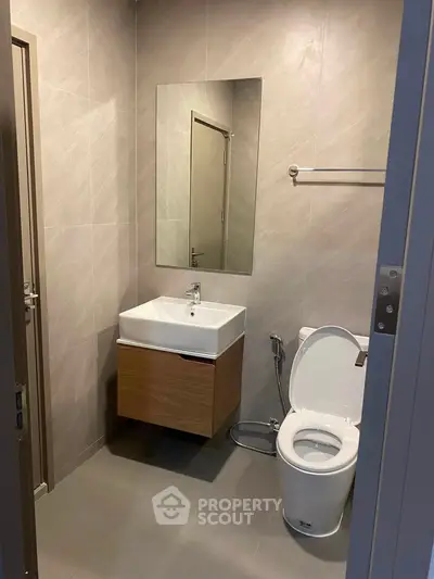 Modern bathroom with sleek fixtures and neutral tones, featuring a wall-mounted sink and toilet.