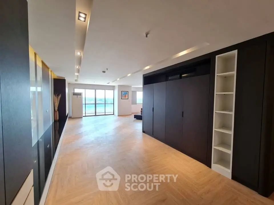 Spacious modern living room with elegant wood flooring and large windows offering stunning views.