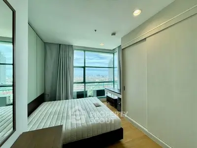 Modern bedroom with large window offering stunning city view, featuring minimalist decor and ample natural light.